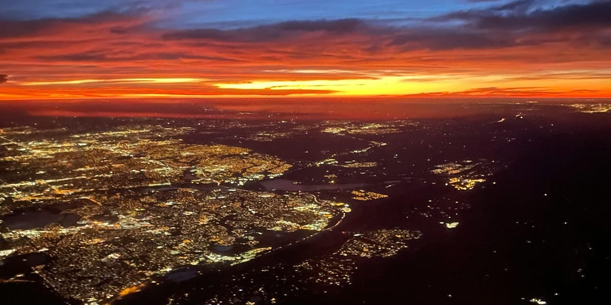 An areal image of a city with the sun on the horizon.