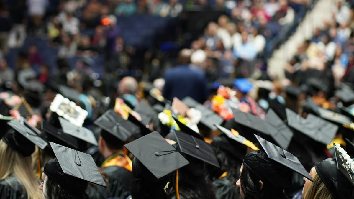 An image of a college commencement ceremony with attendees dressed in their graduation robes and hats.